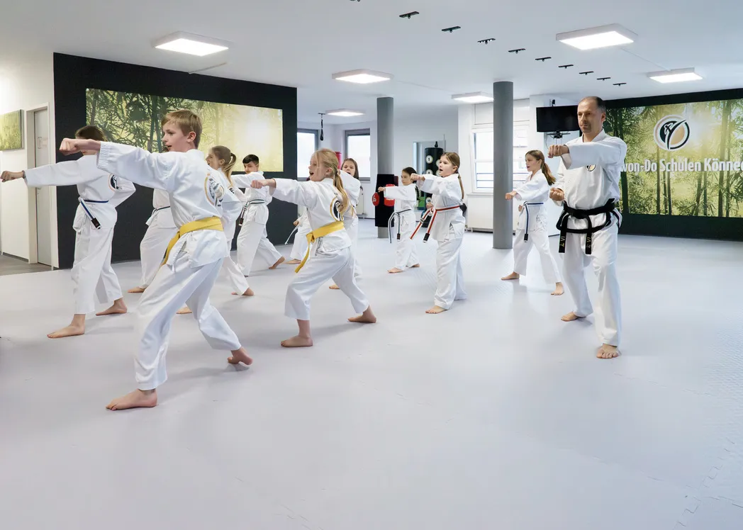 Trainer führt eine Gruppe von Tiger-Kids durch eine Stoßtechnik-Serie im Trainingsraum